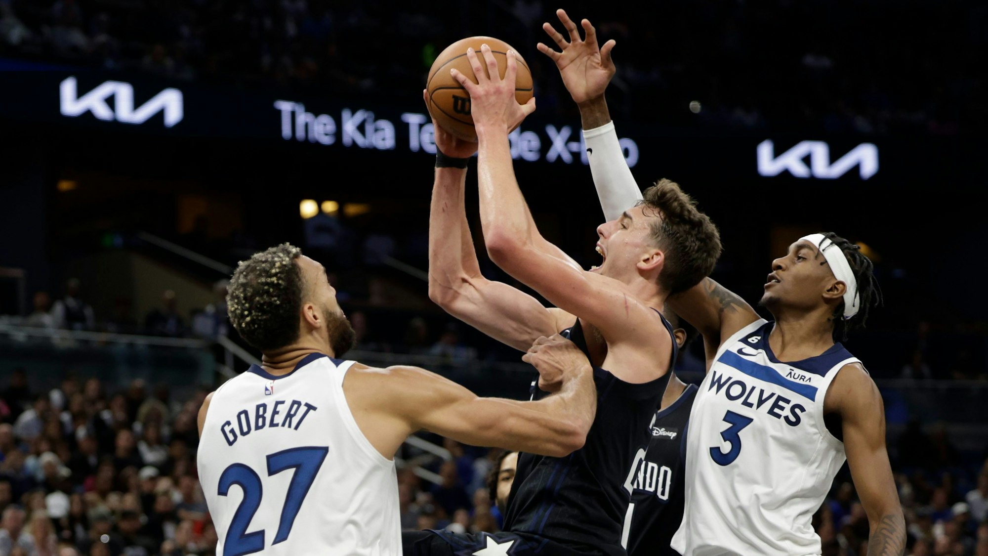 Franz Wagner (22) von den Orlando Magic wirft zwischen Minnesota Timberwolves-Center Rudy Gobert (27) und Forward Jaden McDaniels (3).