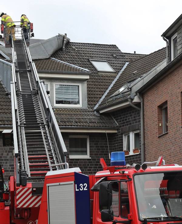 Feuerwehrleute befestigen ein vom Sturm gelöstes Teil eines Daches.