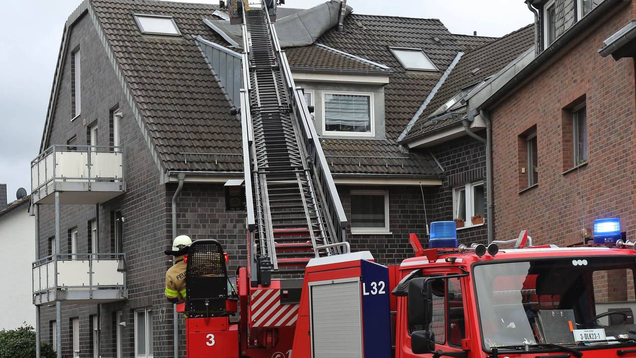 Feuerwehrleute befestigen ein vom Sturm gelöstes Teil eines Daches.