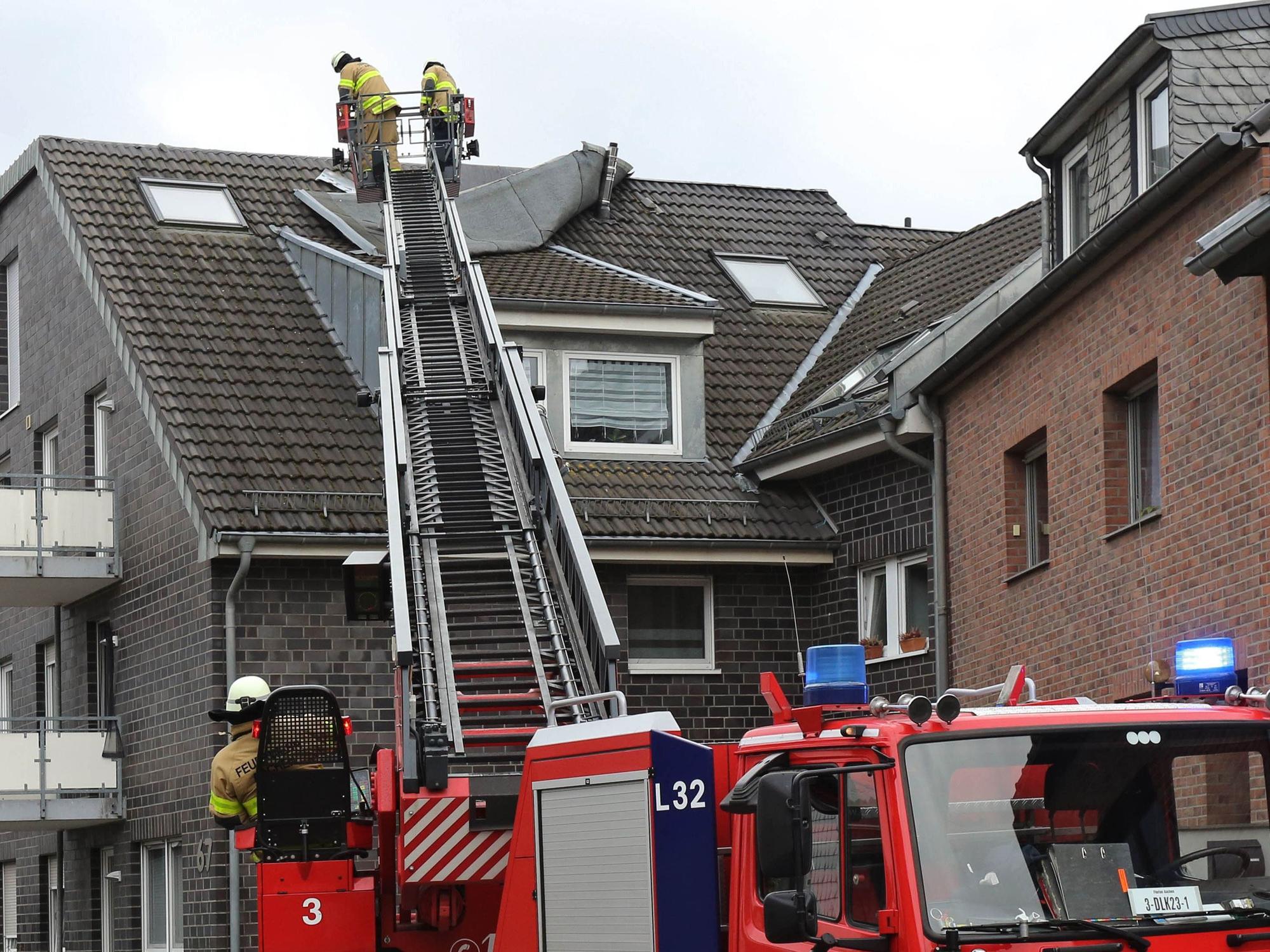 Feuerwehrleute befestigen ein vom Sturm gelöstes Teil eines Daches.