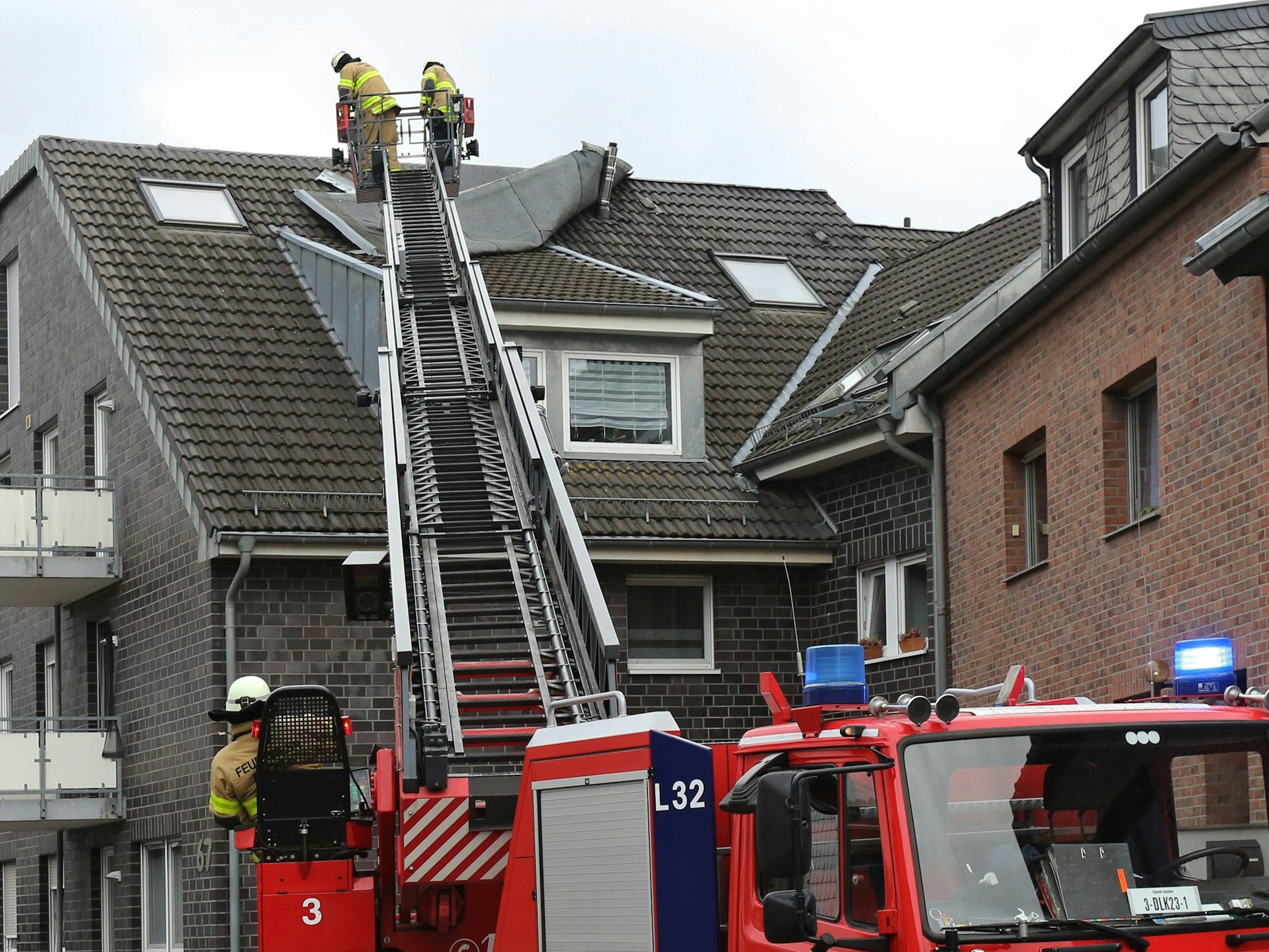Feuerwehrleute befestigen ein vom Sturm gelöstes Teil eines Daches.