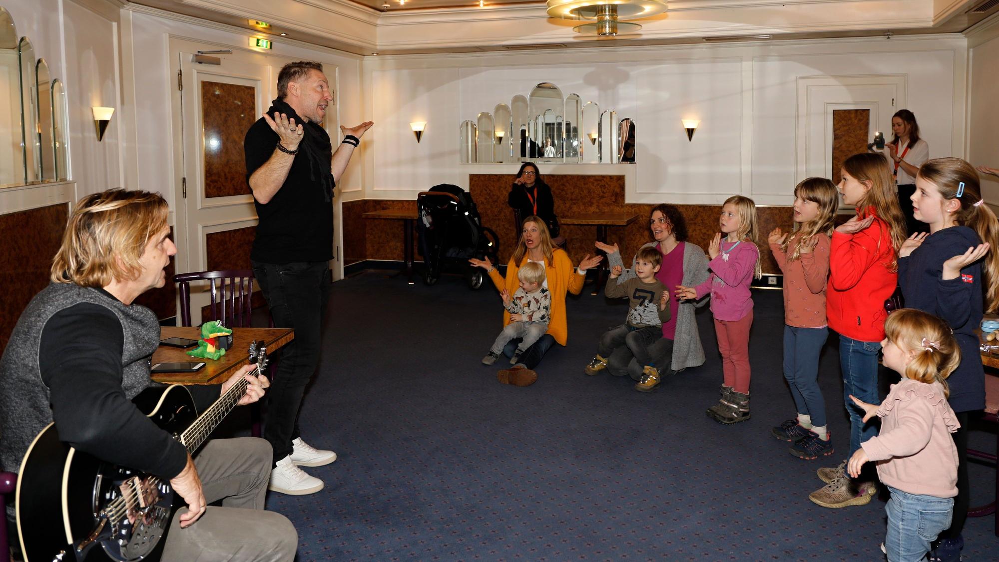 Zwei Mitglieder der Höhner singen und tanzen mit Kindern. Die Band hatte zu einem Workshop eingeladen.