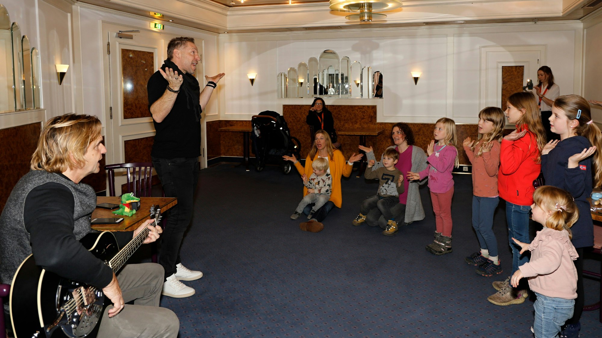 Zwei Mitglieder der Höhner singen und tanzen mit Kindern. Die Band hatte zu einem Workshop eingeladen.