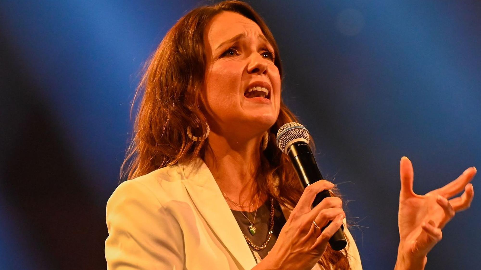 Carolin Kebekus steht auf der Bühne und spricht ins Mikrofon.