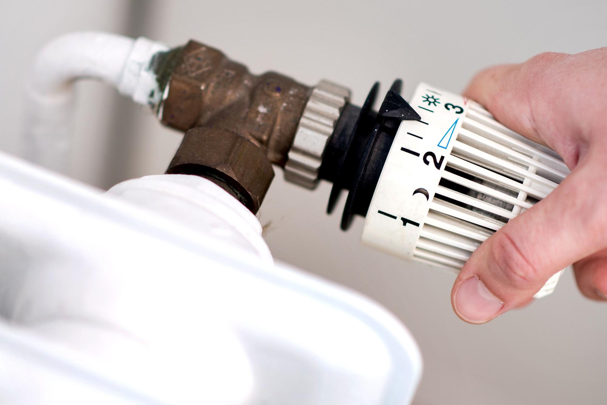 Eine Frau dreht im März 2019 am Thermostat einer Heizung.