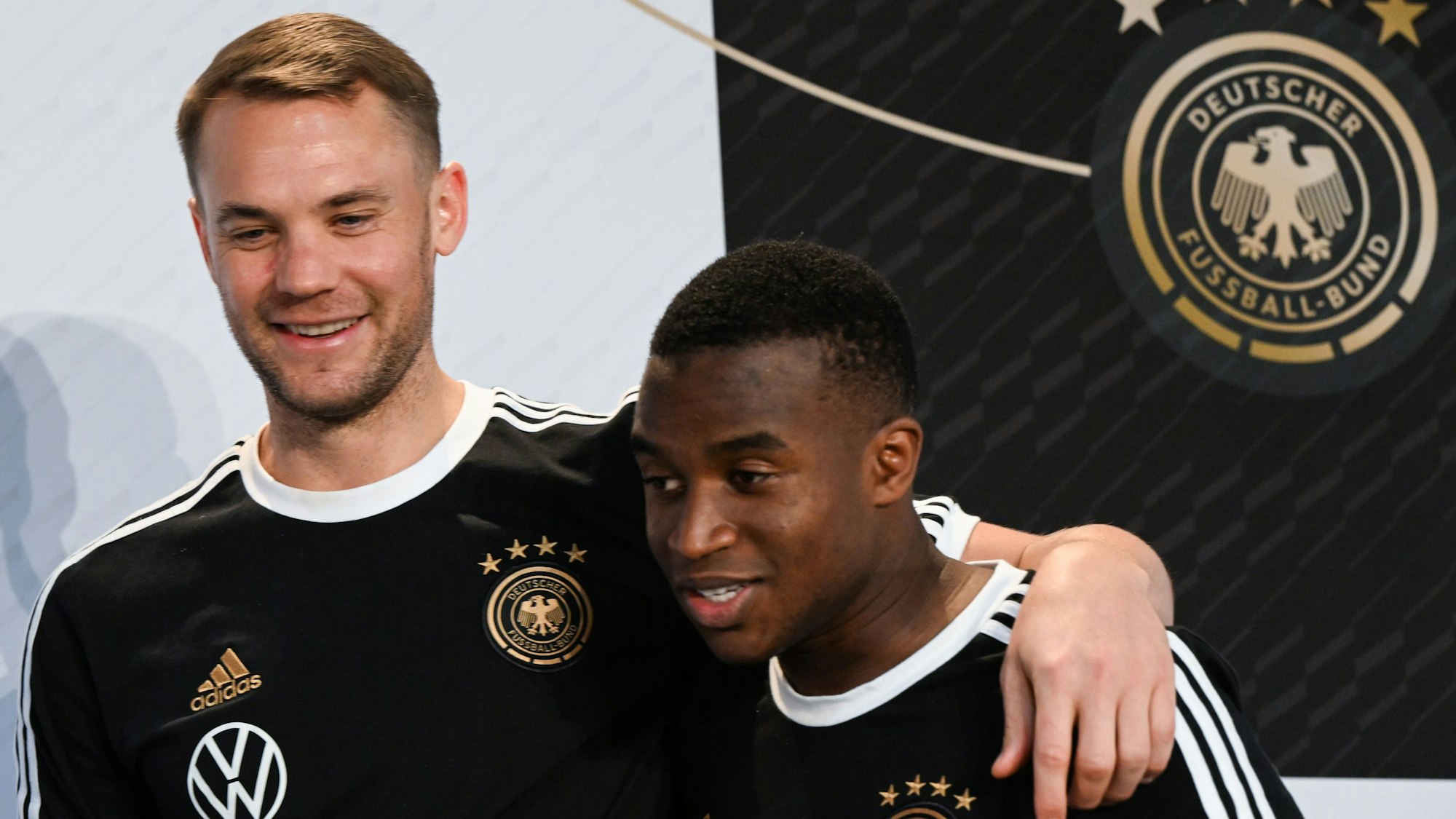 Youssoufa Moukoko (r) und Torhüter Manuel Neuer bei einer Pressekonferenz.