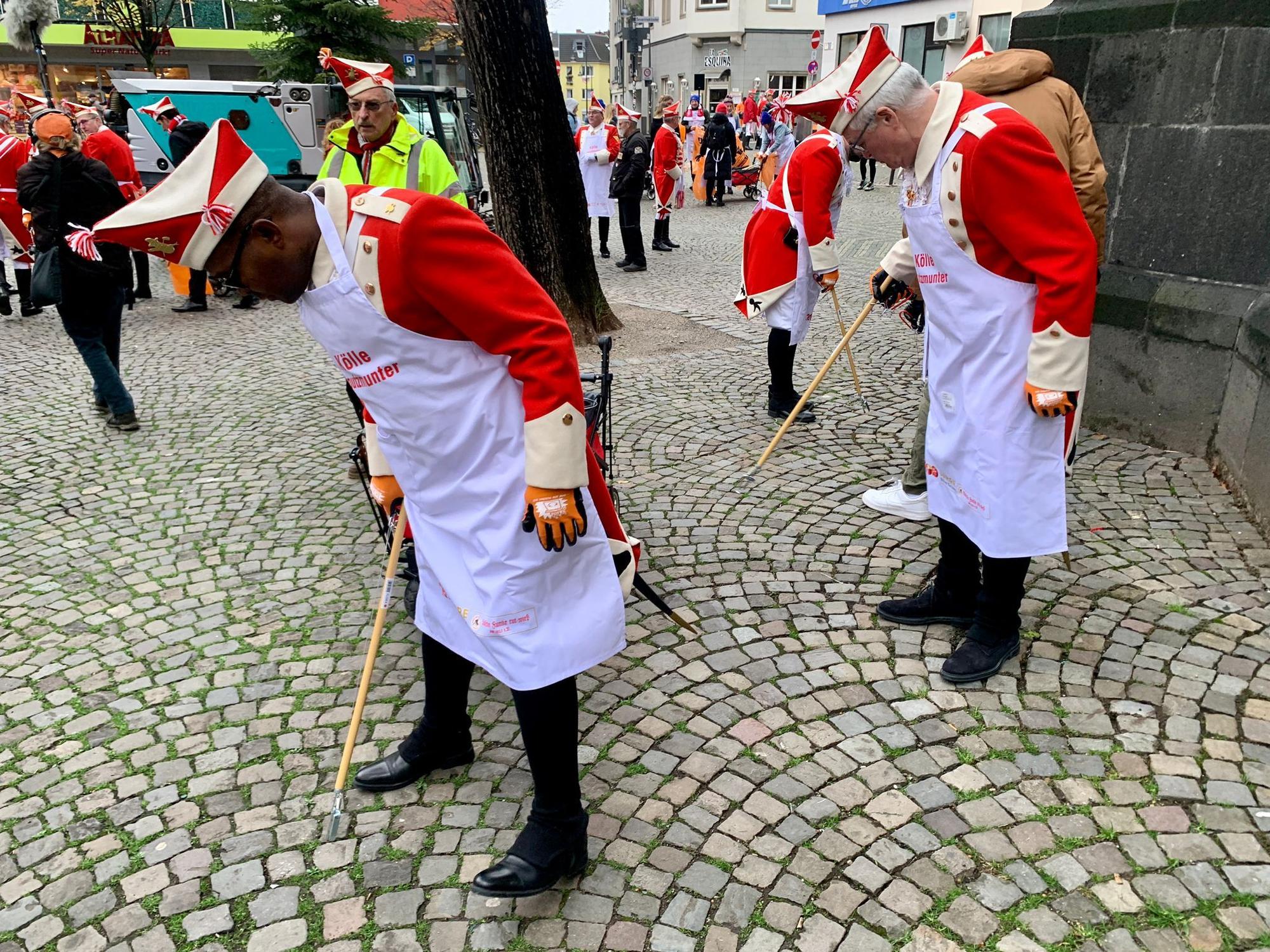 Mitglieder der Roten Funken sammeln Müll auf.