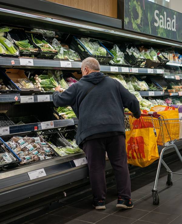 Ein Mann und eine Fraustehen an einem Gemüseregal in einem Supermarkt.
