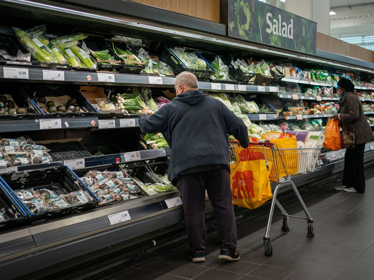 Ein Mann und eine Fraustehen an einem Gemüseregal in einem Supermarkt.