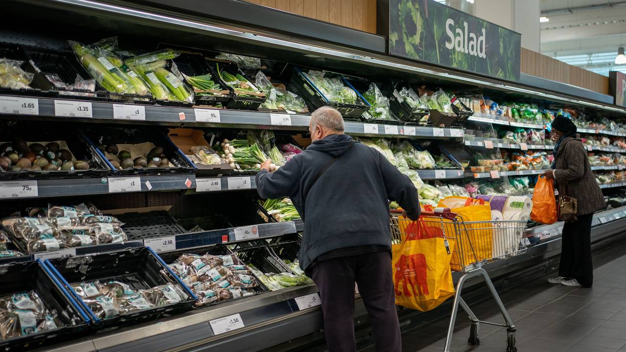 Ein Mann und eine Fraustehen an einem Gemüseregal in einem Supermarkt.