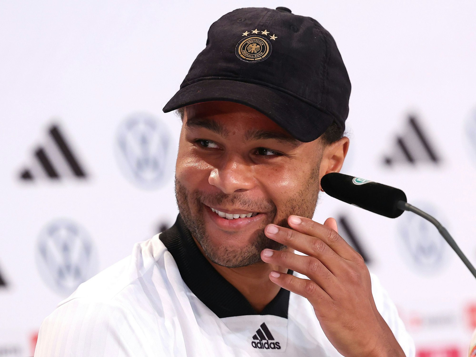 Serge Gnabry sitzt bei der Pressekonferenz.