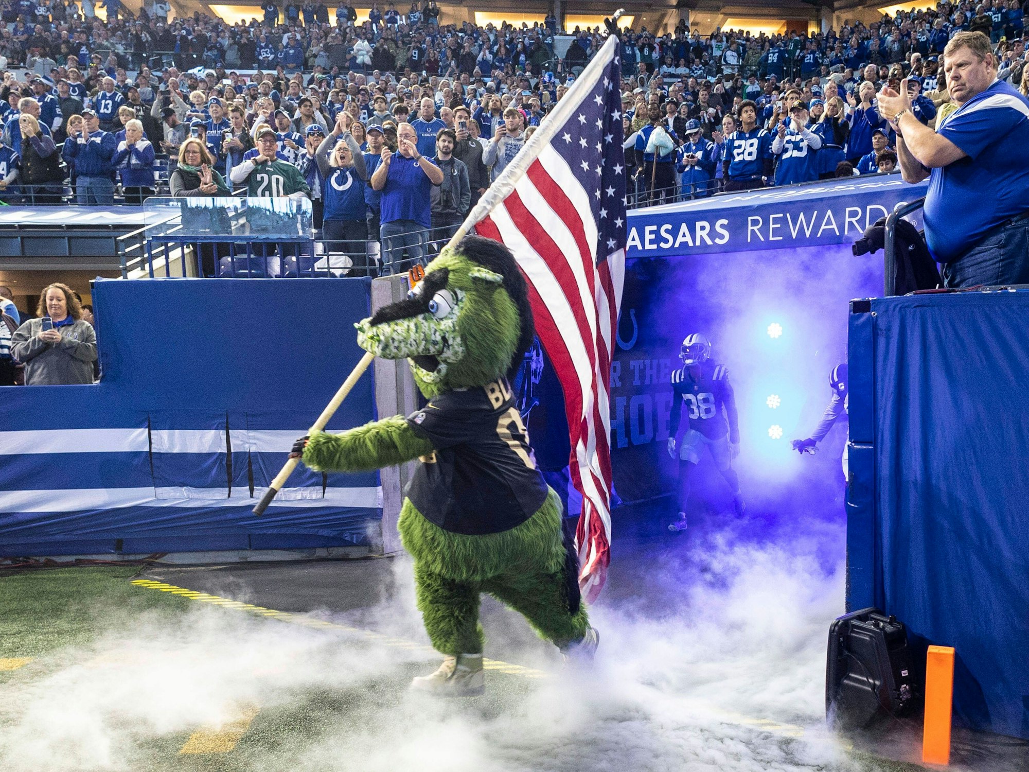 NFL-Maskottchen Blue läuft mit einer USA-Flagge auf den Rasen.