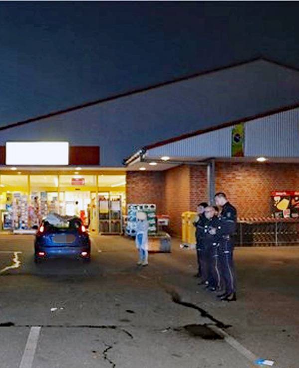 Polizei und einige Autos stehen auf einem Parkplatz vor einem Supermarkt. Der Mann, der hier angefahren wurde, ist mittlerweile tot.