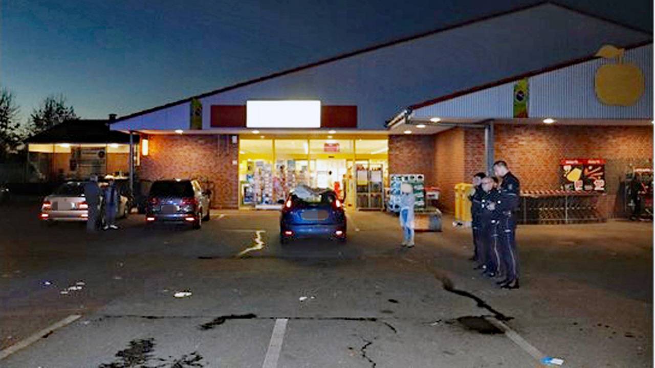 Polizei und einige Autos stehen auf einem Parkplatz vor einem Supermarkt. Der Mann, der hier angefahren wurde, ist mittlerweile tot.
