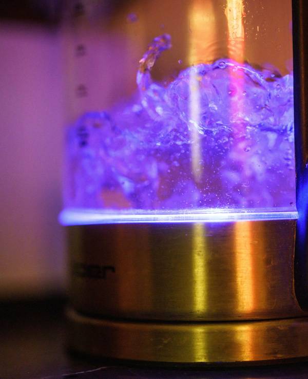Von einer eingebauten Lampe blau beleuchtet ist kochendes Teewasser in einem Wasserkocher.