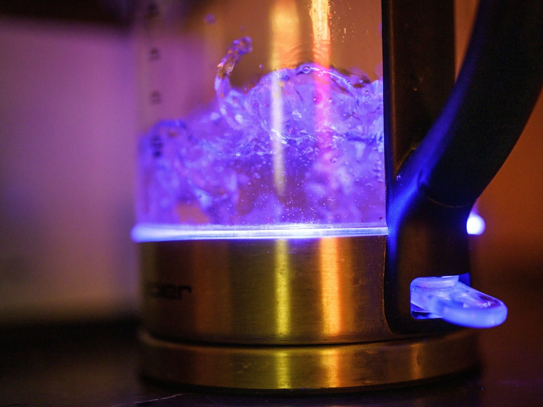 Von einer eingebauten Lampe blau beleuchtet ist kochendes Teewasser in einem Wasserkocher.