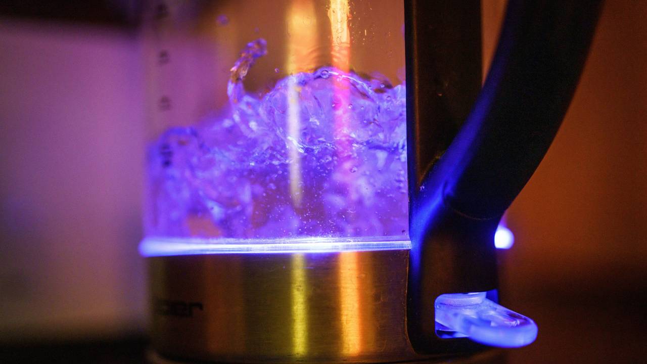 Von einer eingebauten Lampe blau beleuchtet ist kochendes Teewasser in einem Wasserkocher.