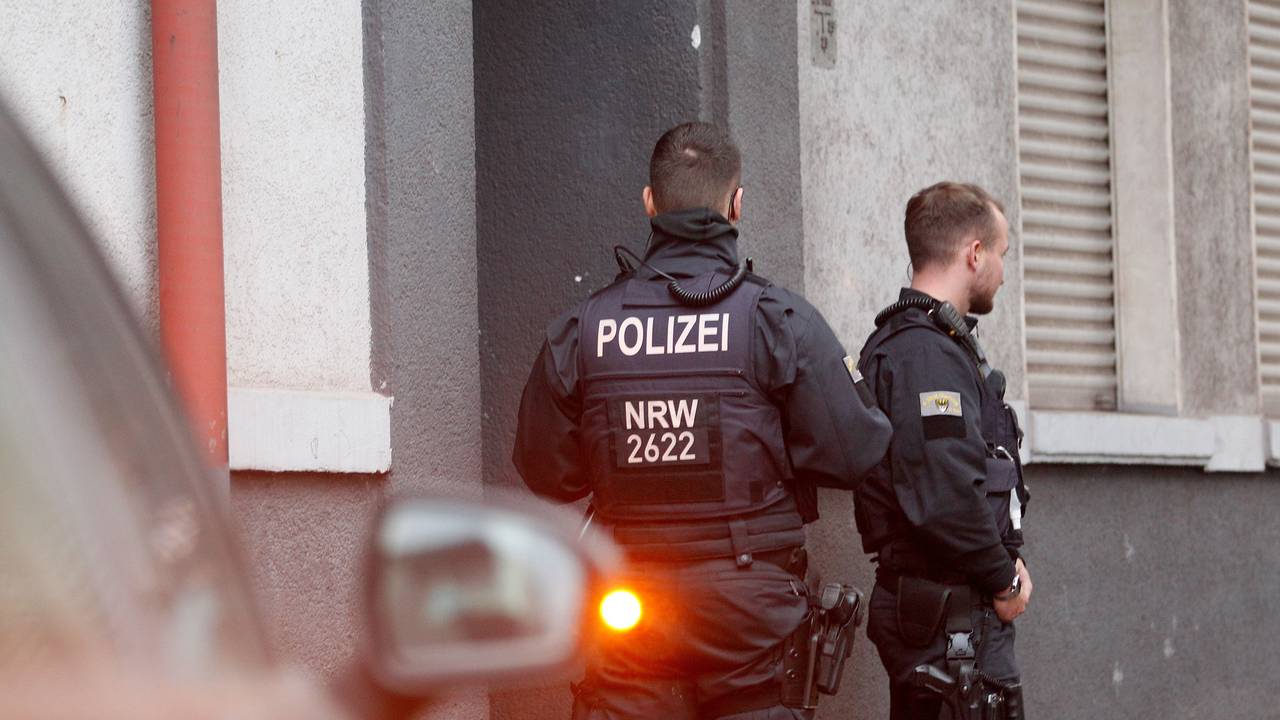 Zwei Polizeibeamte sichern bei einer Razzia einen Hauseingang ab.