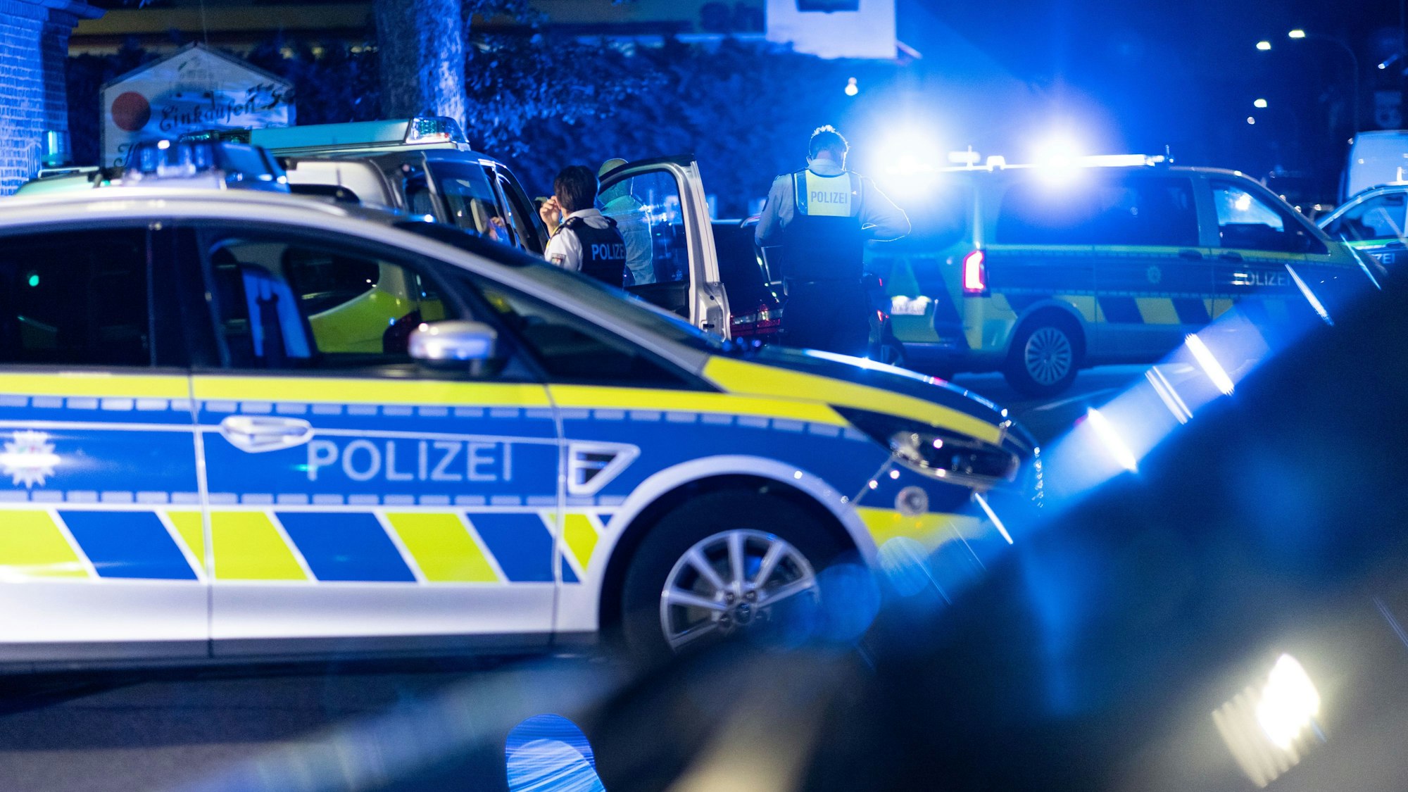 Einsatzkräfte der Polizei stehen vor einer Tankstelle.