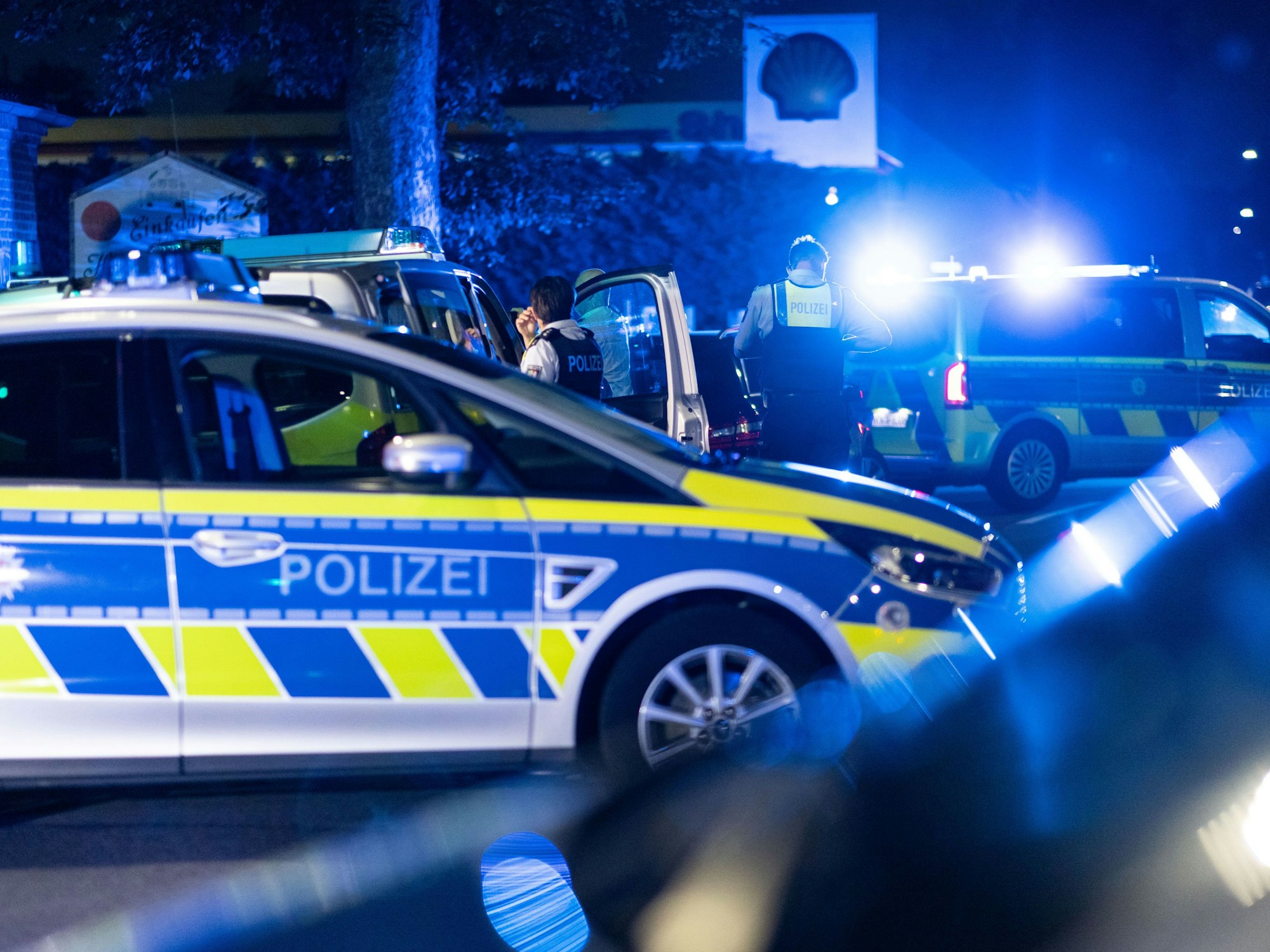 Einsatzkräfte der Polizei stehen vor einer Tankstelle.