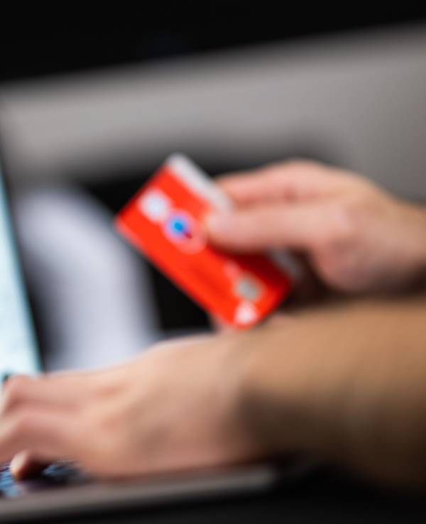 Eine Person hält seine Bankkarte beim Online-Shopping bereit.