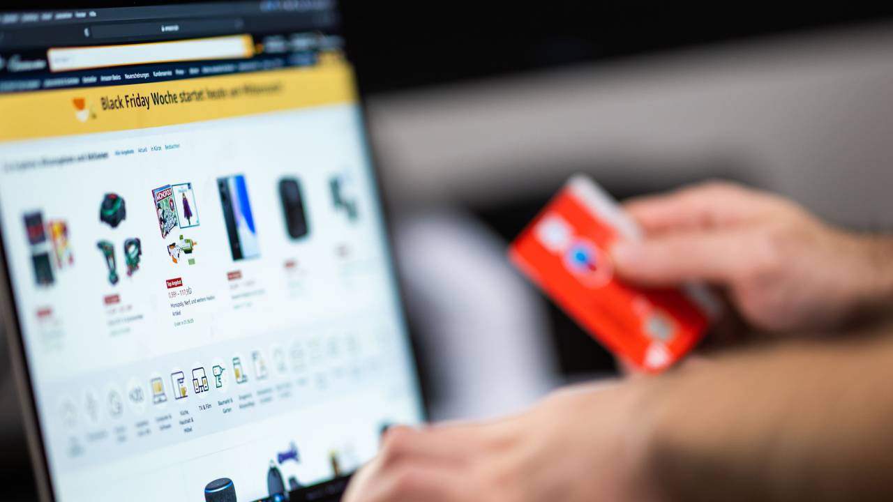 Eine Person hält seine Bankkarte beim Online-Shopping bereit.