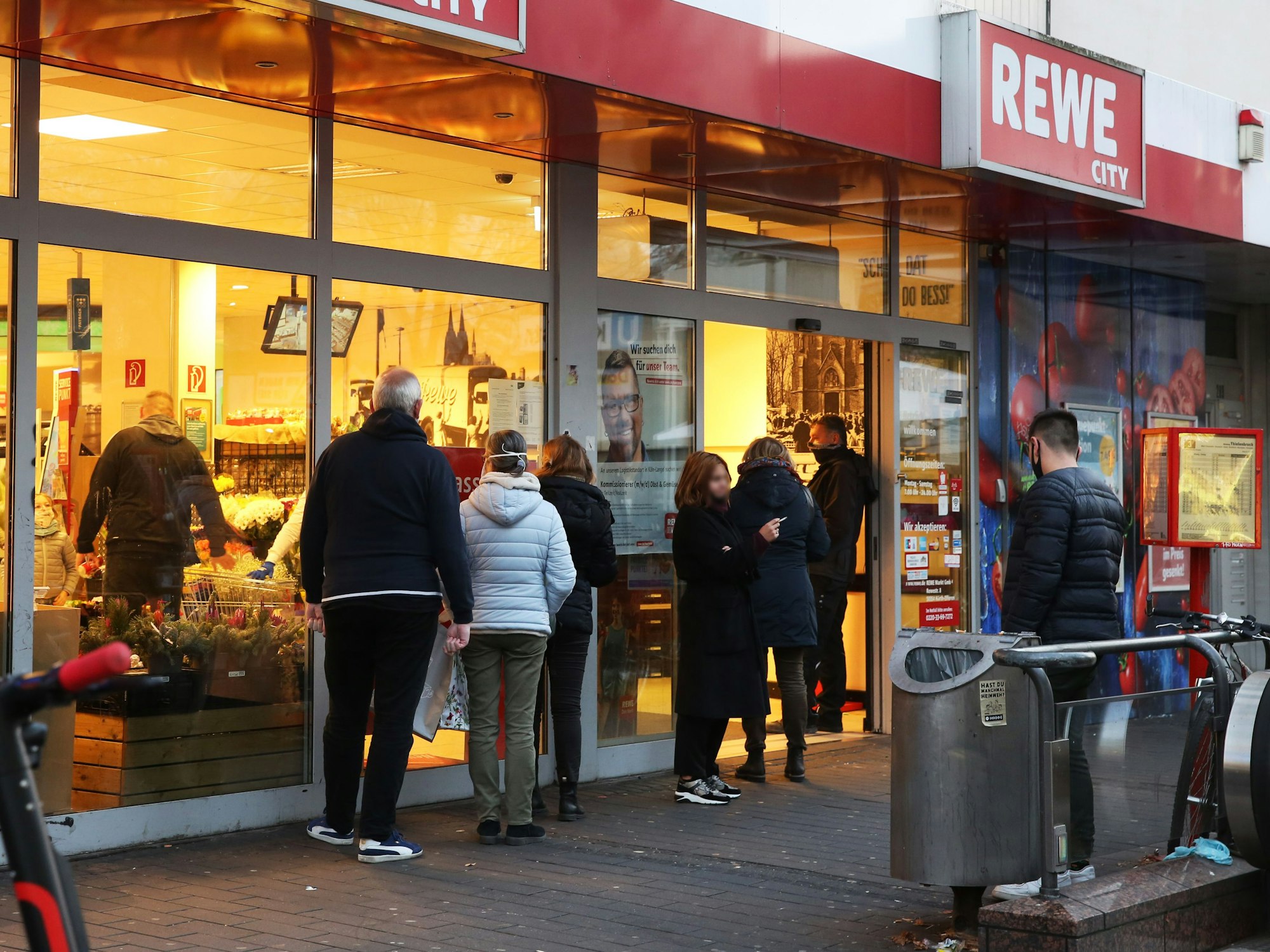 Menschen warten in Köln vor einer Rewe-Filiale und werden einzeln rein gelassen.
