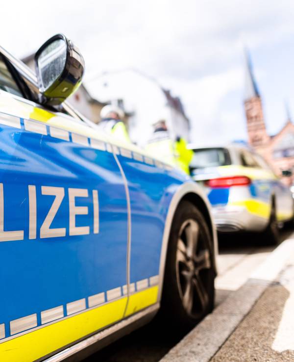 Zwei Einsatzfahrzeuge der Polizei stehen in Freiburg am Straßenrand.