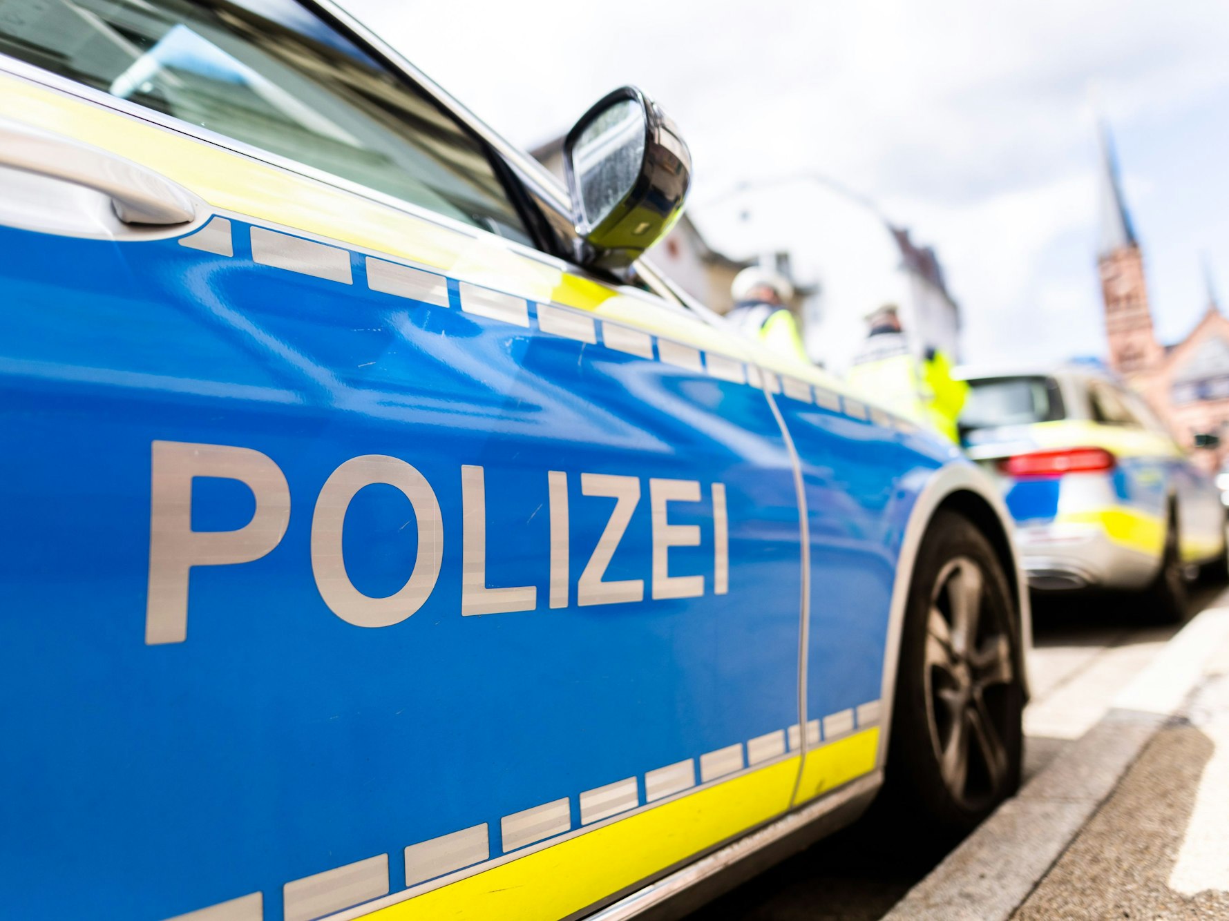 Zwei Einsatzfahrzeuge der Polizei stehen in Freiburg am Straßenrand.