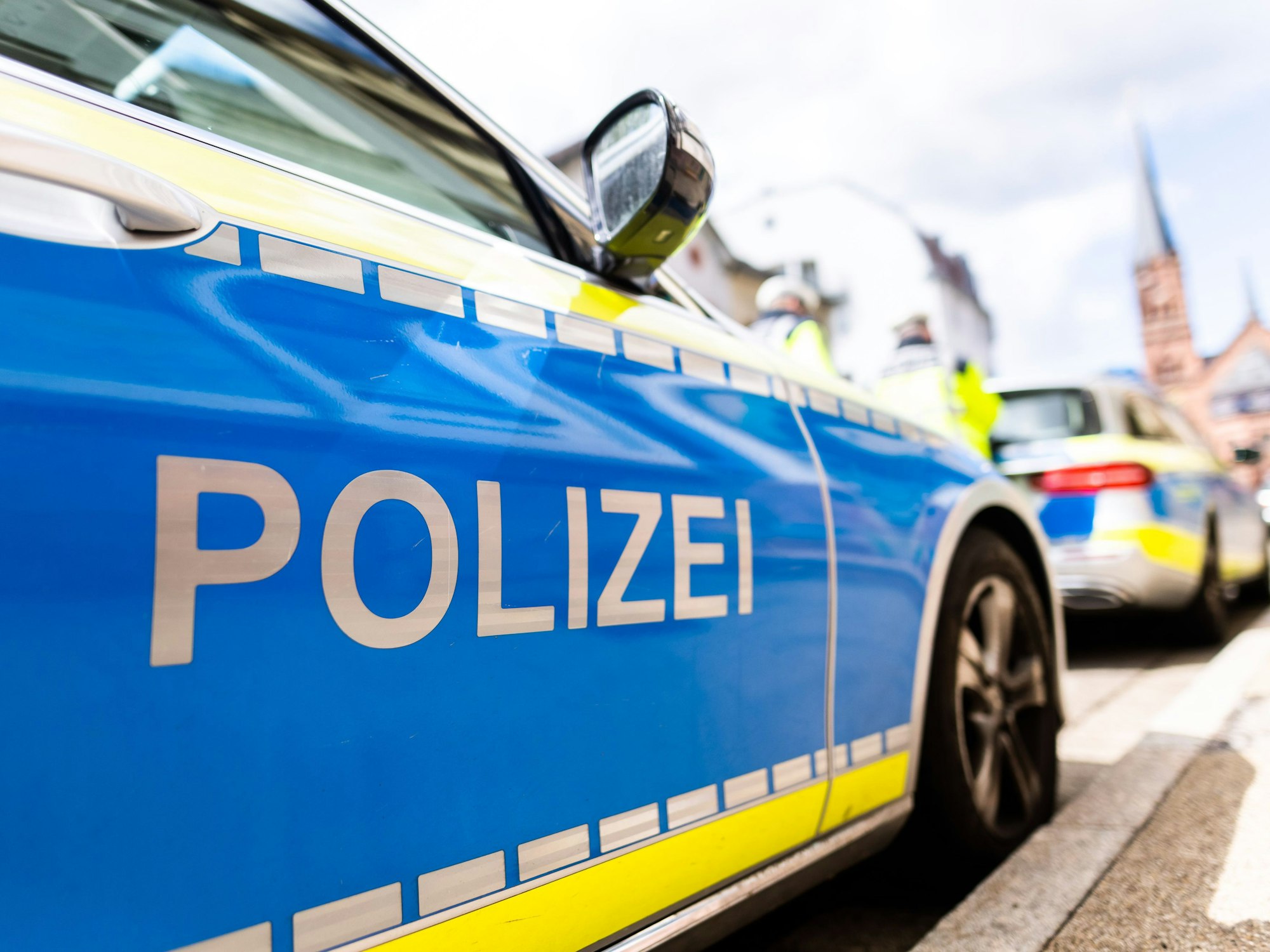 Zwei Einsatzfahrzeuge der Polizei stehen in Freiburg am Straßenrand.