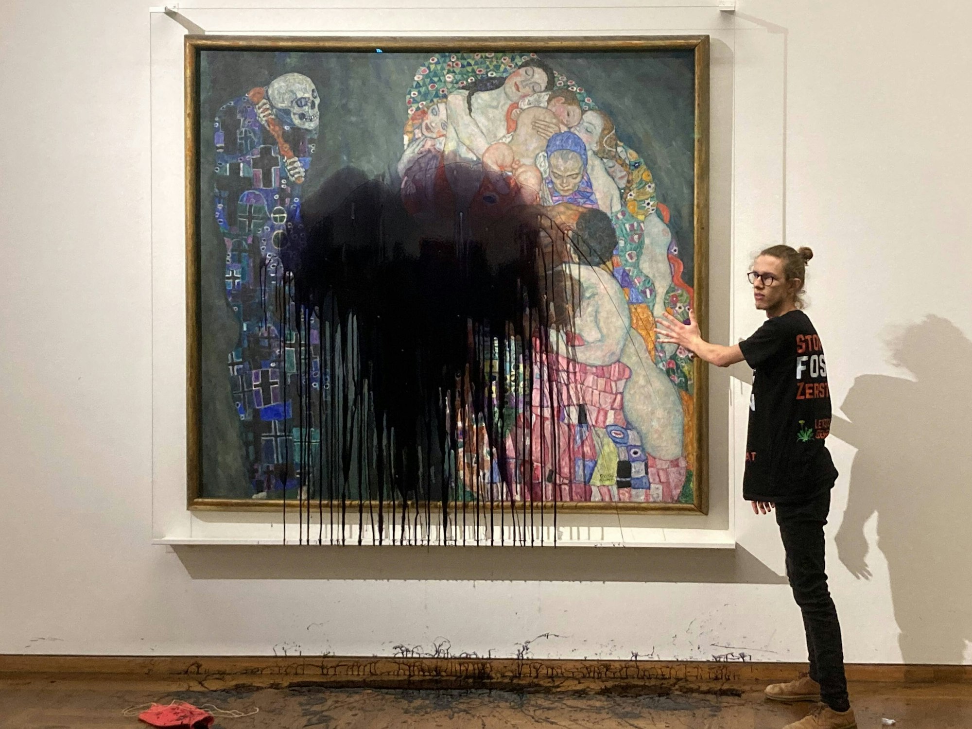 Ein Aktivist wirft schwarze Farbe auf ein Gemälde in einem Museum.