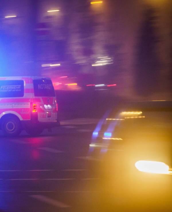 Mit eingeschaltetem Blaulicht fährt ein Rettungswagen am Morgen über eine Kreuzung, die noch im Nebel liegt.