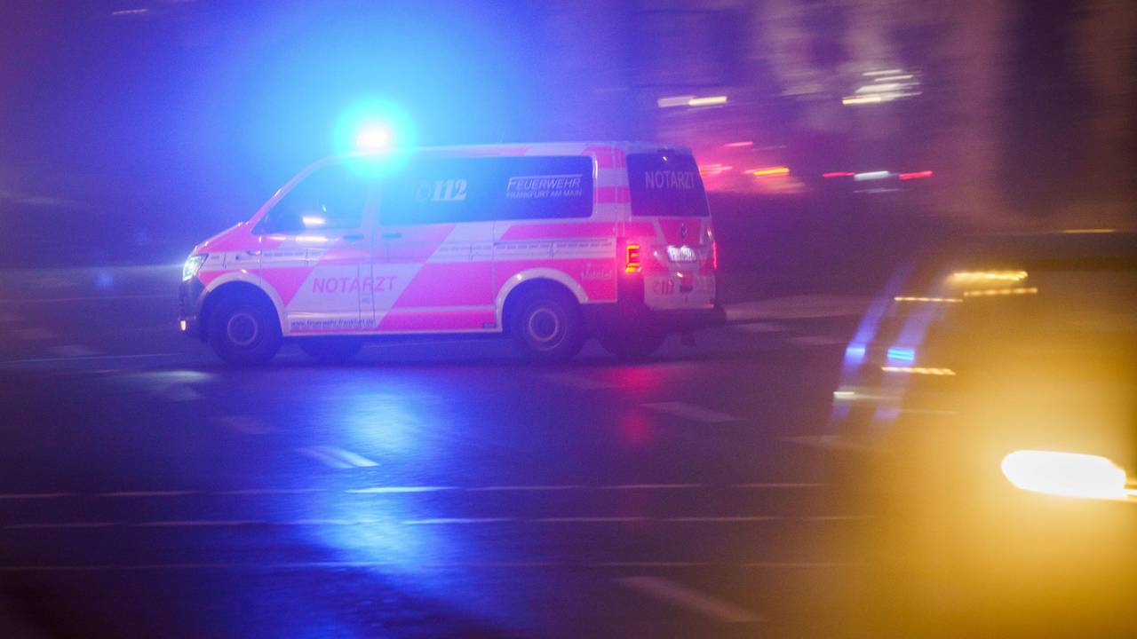 Mit eingeschaltetem Blaulicht fährt ein Rettungswagen am Morgen über eine Kreuzung, die noch im Nebel liegt.