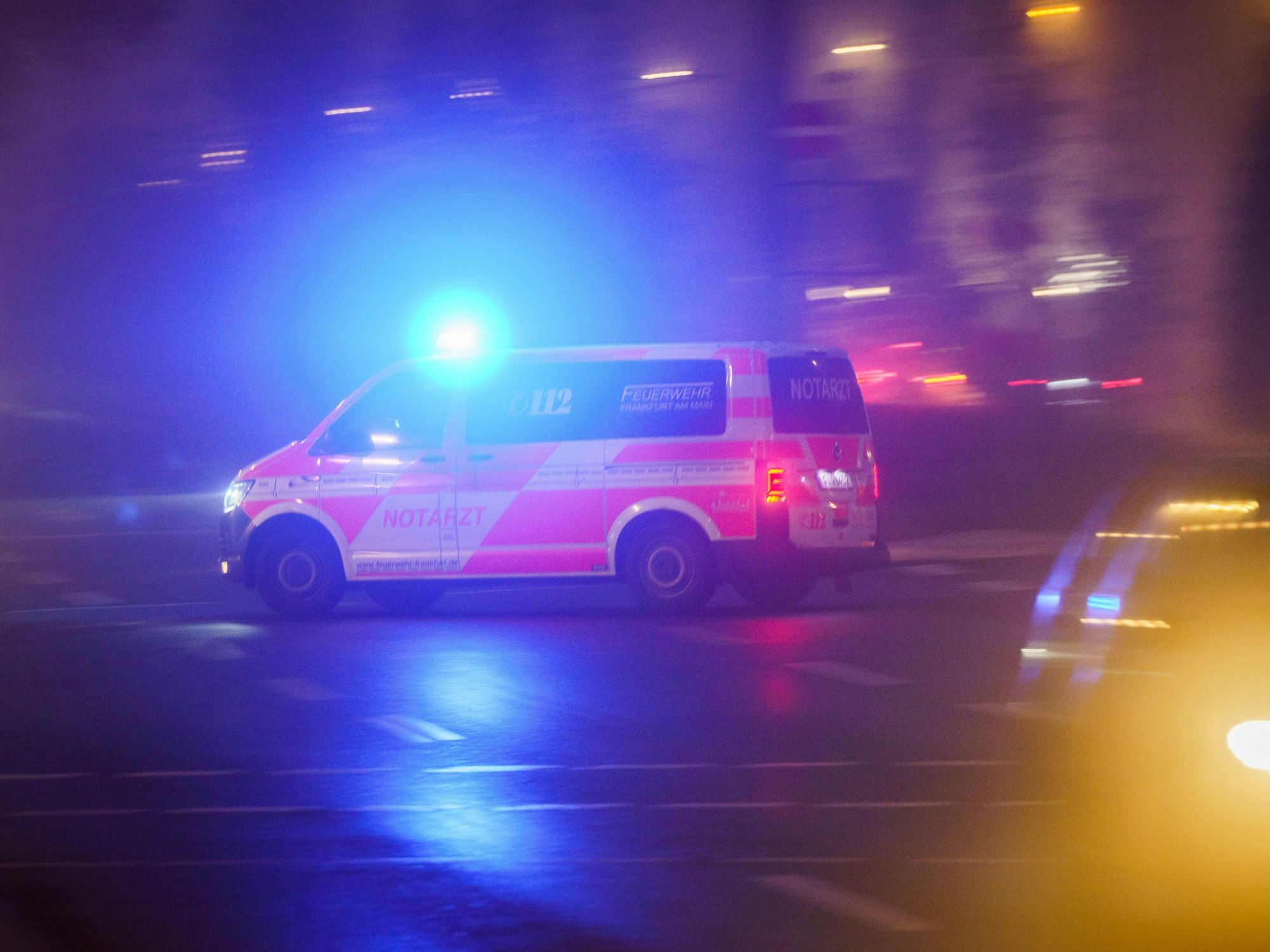 Mit eingeschaltetem Blaulicht fährt ein Rettungswagen am Morgen über eine Kreuzung, die noch im Nebel liegt.