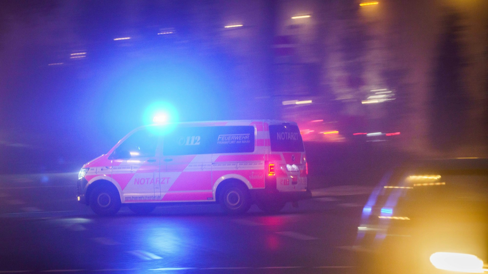 Mit eingeschaltetem Blaulicht fährt ein Rettungswagen am Morgen über eine Kreuzung, die noch im Nebel liegt.