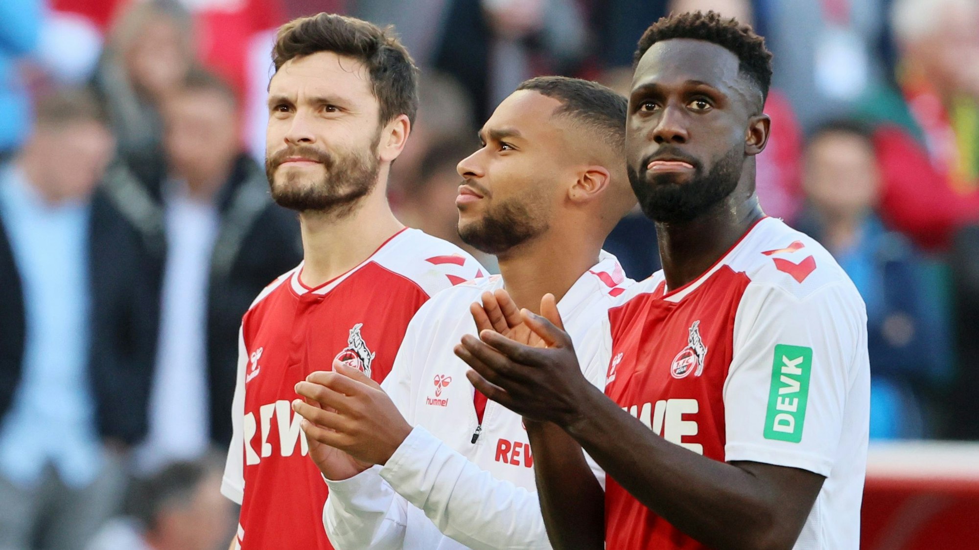 Kingsley Schindler stet mit Linton Maina und Jonas Hector nach dem Bundesliga-Heimspiel des 1. FC Köln gegen Borussia Dortmund vor der Südkurve.