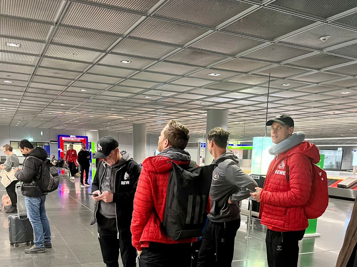 Profis und Betreuer des 1. FC Köln stehen am Donnerstag am Frankfurter Flughafen.
