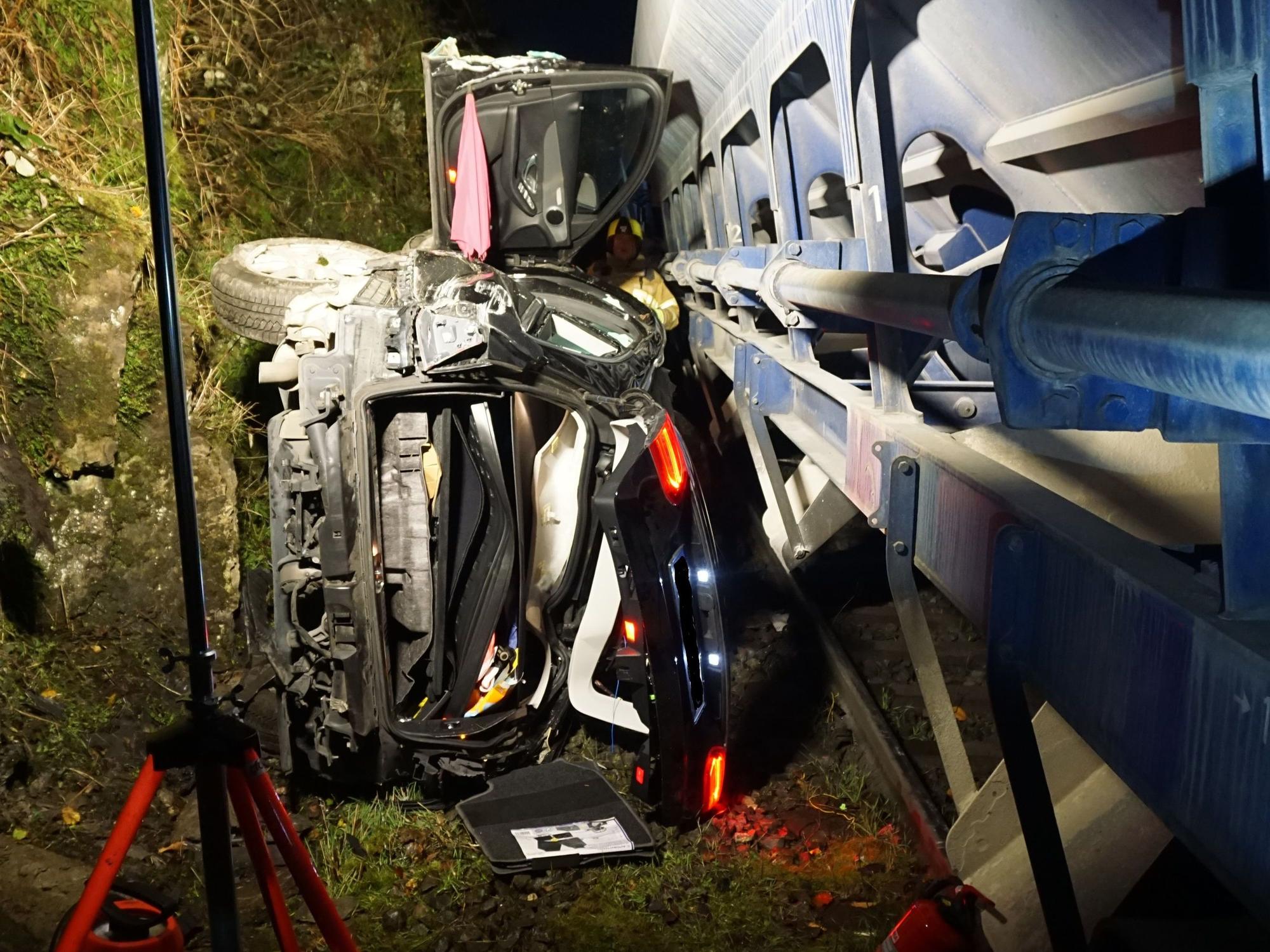 Zerstörtes Auto liegt auf der Seite und sieht zerstört aus. Es wurde von einem Güterzug erfasst.