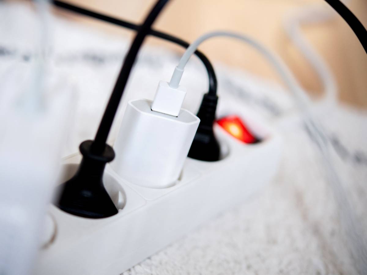 Die Netzstecker mehrerer Elektrogeräte stecken in einer Steckdosenleiste in einem Wohnzimmer. Viele Stromversorger erhöhen die Preise ab Januar 2023.