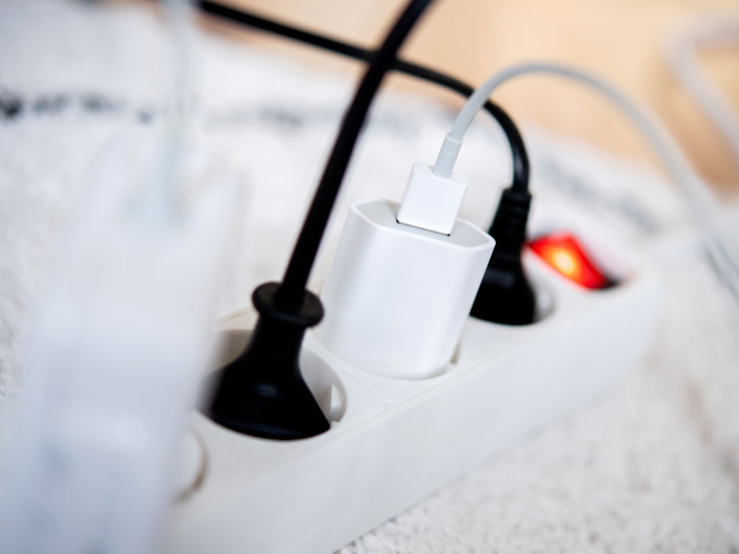 Die Netzstecker mehrerer Elektrogeräte stecken in einer Steckdosenleiste in einem Wohnzimmer. Viele Stromversorger erhöhen die Preise ab Januar 2023.