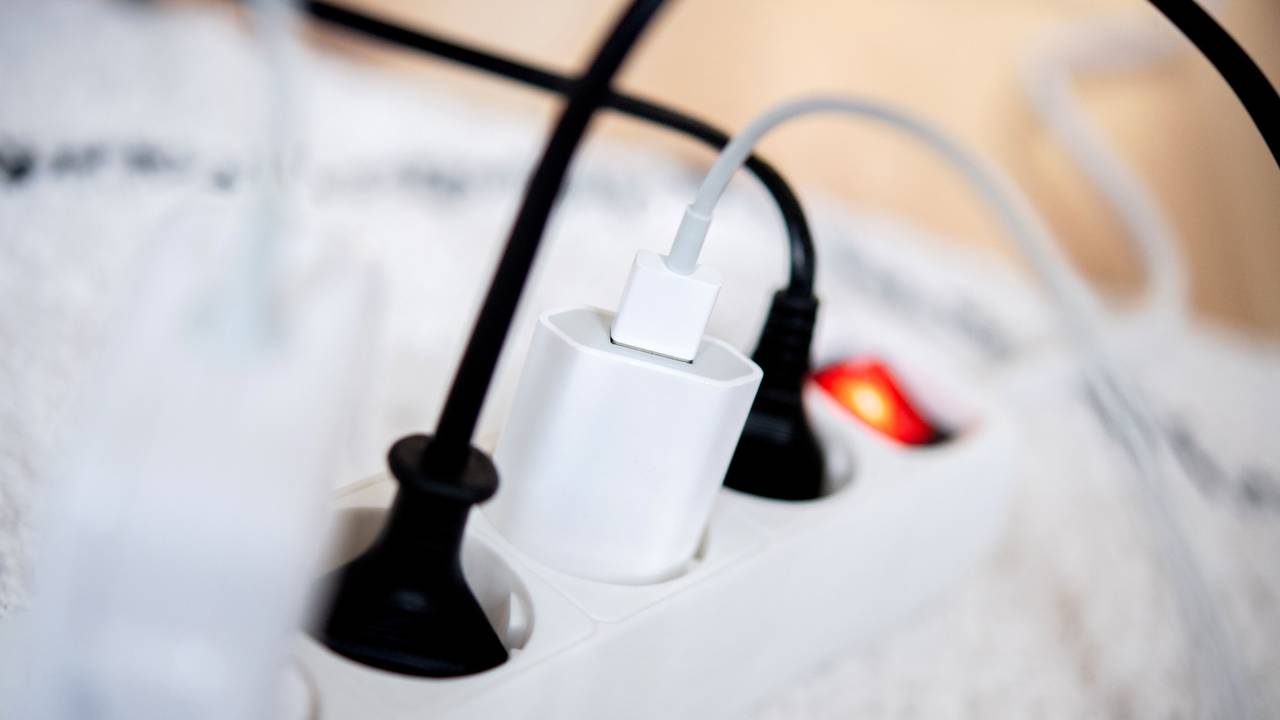 Die Netzstecker mehrerer Elektrogeräte stecken in einer Steckdosenleiste in einem Wohnzimmer. Viele Stromversorger erhöhen die Preise ab Januar 2023.