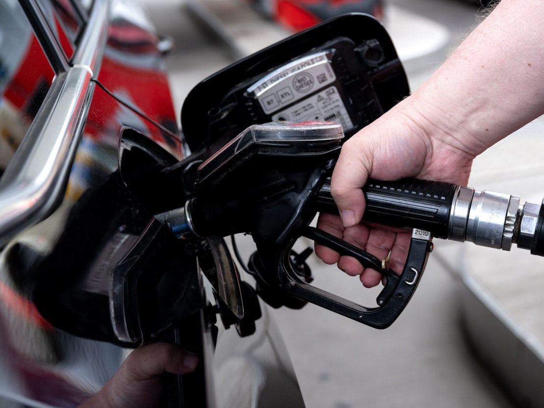 Ein Mann hält eine Zapfpistole an einer Tankstelle in der Hand und betankt sein Auto.