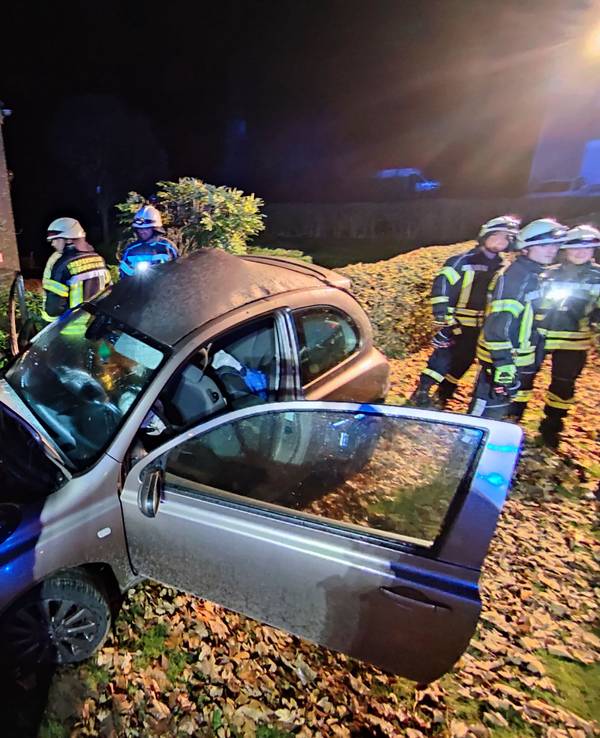 Kleinwagen mit offener Motorhaube steht in einem Vorgarten, daneben zahlreiche Einsatzkräfte der Feuerwehr.
