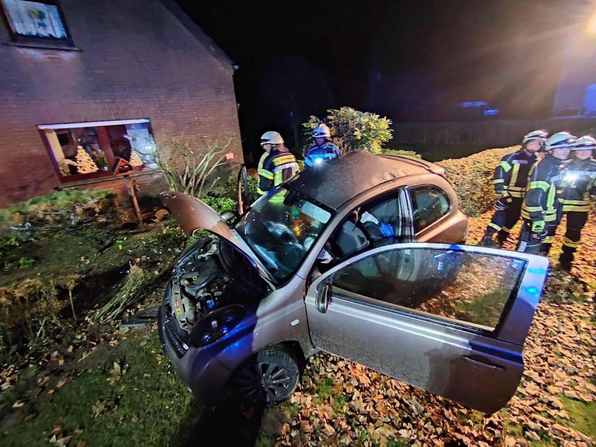 Kleinwagen mit offener Motorhaube steht in einem Vorgarten, daneben zahlreiche Einsatzkräfte der Feuerwehr.
