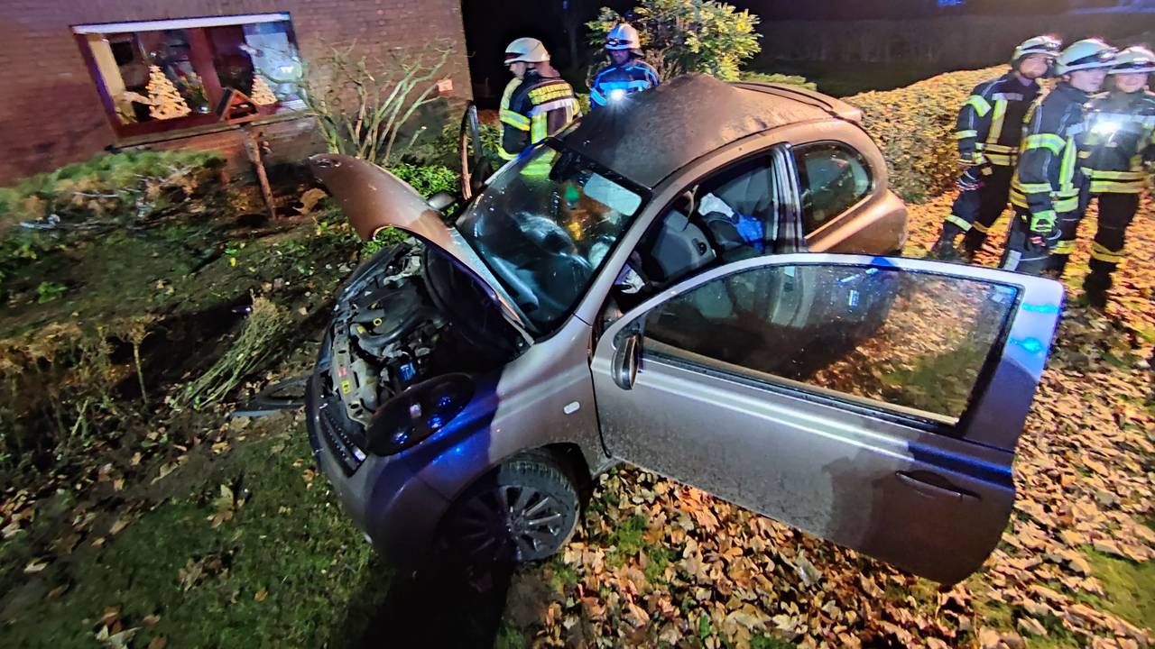 Kleinwagen mit offener Motorhaube steht in einem Vorgarten, daneben zahlreiche Einsatzkräfte der Feuerwehr.