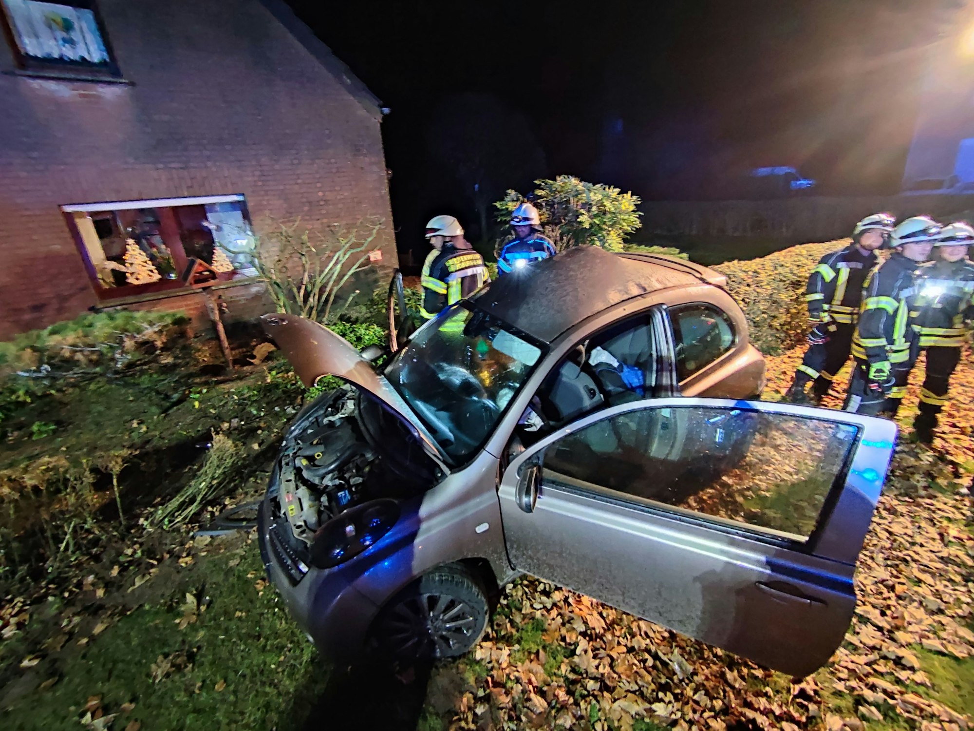 Kleinwagen mit offener Motorhaube steht in einem Vorgarten, daneben zahlreiche Einsatzkräfte der Feuerwehr.