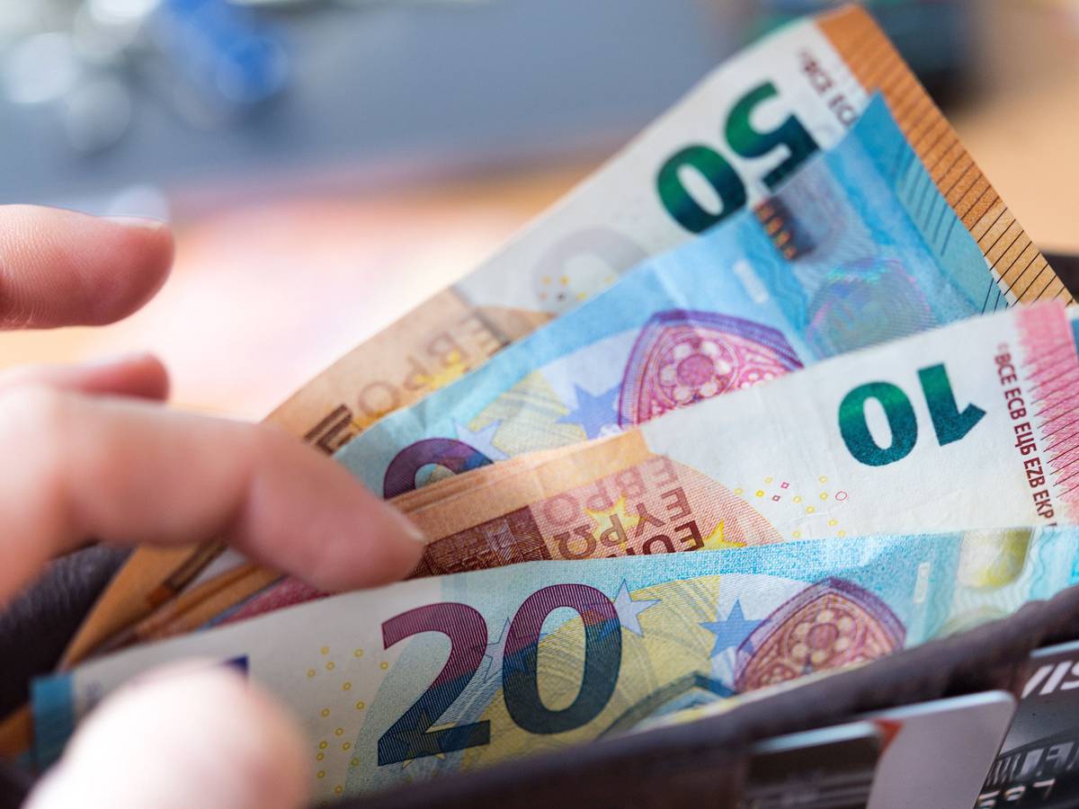 Eine Frau hält eine Geldbörse mit Banknoten in der Hand.