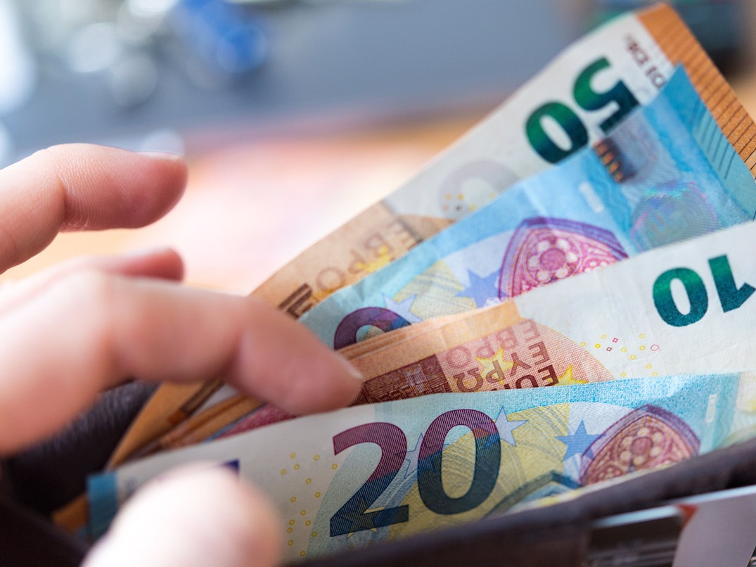 Eine Frau hält eine Geldbörse mit Banknoten in der Hand.