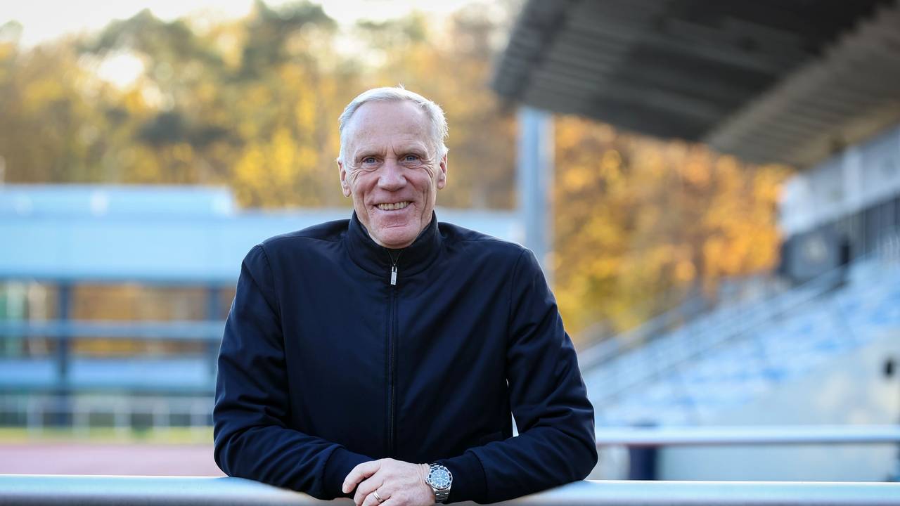 Ingo Froböse lehnt sich im Stadion der Sporthochschule Köln über eine Barriere und schaut in die Kamera.
