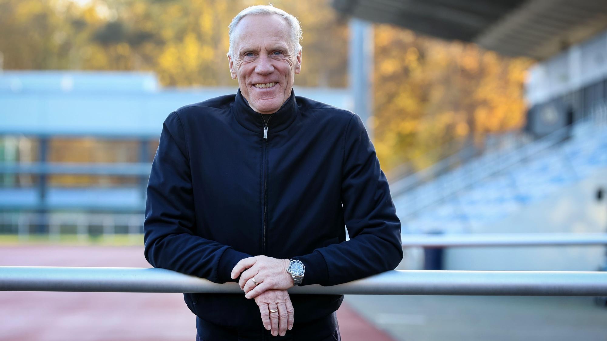 Ingo Froböse lehnt sich im Stadion der Sporthochschule Köln über eine Barriere und schaut in die Kamera.